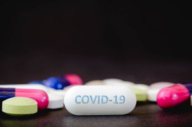 Bu resimli ilaç hapları ve COVID-19 metni bir hapta.