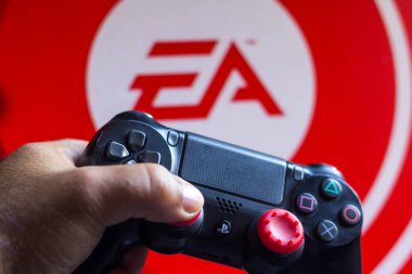 17 Mayıs 2021, Brezilya. Bu resimde PlayStation (PS) için denetleyici ve arka planda şirket logosu Elektronik Sanatlar (EA)