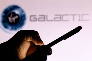 19 Mayıs 2021, Brezilya. Bu resimde Bakire Galaktik logo arka planda bir siluet elin cep telefonu tutarken görülüyor.