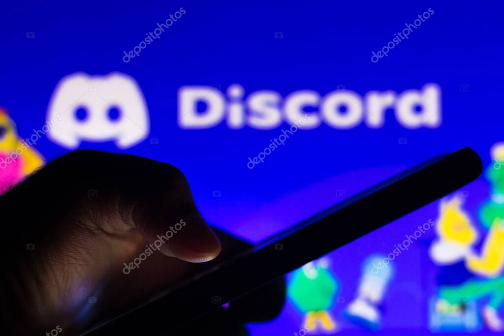 May 21, 2021, Brazil. In this photo illustration the Discord logo app seen in the background of a silhouette hand holding a mobile phone