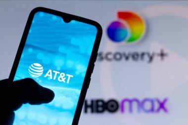 23 Mayıs 2021, Brezilya. Bu resimde AT & Ty logosu bir akıllı telefonda gösteriliyor. Arkaplanda Discovery + (artı) ve HBO Max 'in yayın hizmetlerinin logoları