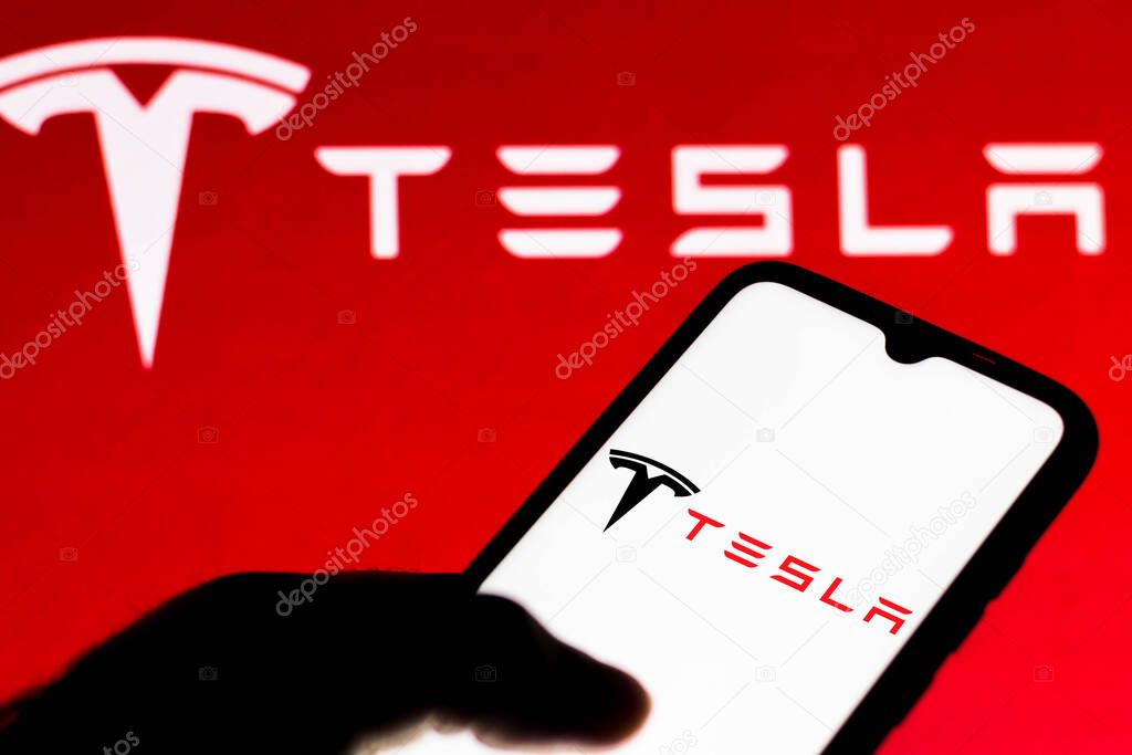 July 18, 2021, Brazil. In this photo illustration the Tesla logo is seen on a smartphone and a pc screen