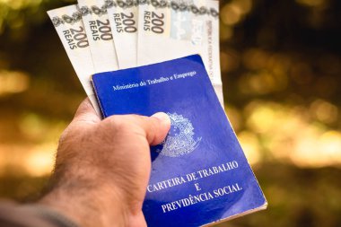 28 Temmuz 2021, Brezilya. Bu resimde bir adam Brezilya 'daki çalışma ve sosyal güvenlik kartını 200 reais' lik dört banknotla gösteriyor.