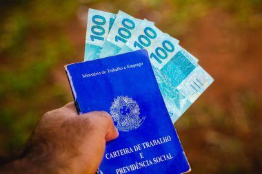 28 Temmuz 2021, Brezilya. Bu resimde bir adam Brezilya 'daki çalışma ve sosyal güvenlik kartını 300 reais banknotla sergiliyor.