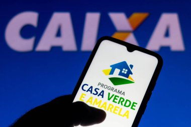 5 Ağustos 2021, Brezilya. Bu resimde akıllı telefondan gösterilen Casa Verde ve Amarela logosu yer almaktadır. Arka planda, Caixa Economica Federal logosu