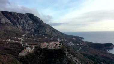 Turuncu çatılarla dağların tepesine uç. Kahverengi çalılar ve ağaçlarla birlikte. Sonbaharda gün batımında deniz kenarında.