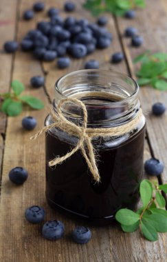 Cam kavanozda yabanmersini reçeli ve ahşap arka planda taze yaban mersini. Dikey yönelim