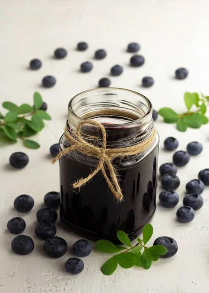 Blåbärssylt och färska blåbär på ljus bakgrund — Stockfoto