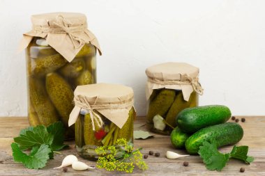 Pickled cucumbers in glass jars on light background. Horizontal orientation