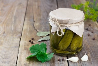 Cam bir kavanozda salatalık turşusu kopyalanmış ahşap arka planda.