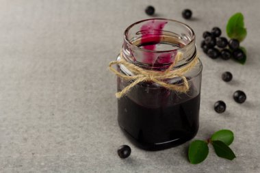 Chokeberry reçeli ve gri arkaplanda fotokopi alanı olan taze böğürtlen. Yatay yönelim