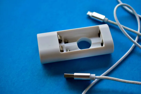 White USB cable and battery charger on a blue background