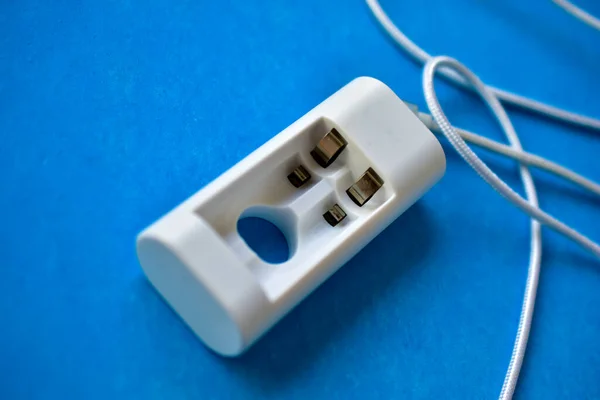 White USB cable and battery charger on a blue background