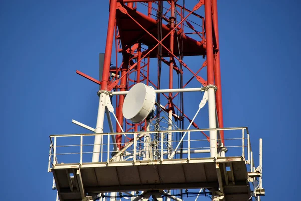 Red and White High rise communication tower Antenna in the city with transmitters