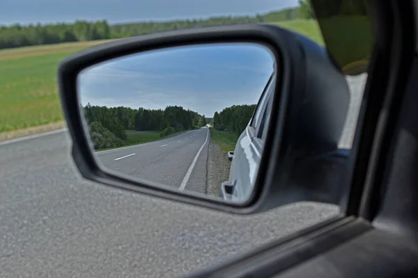 High-speed asphalt road in the reflection of the car mirror