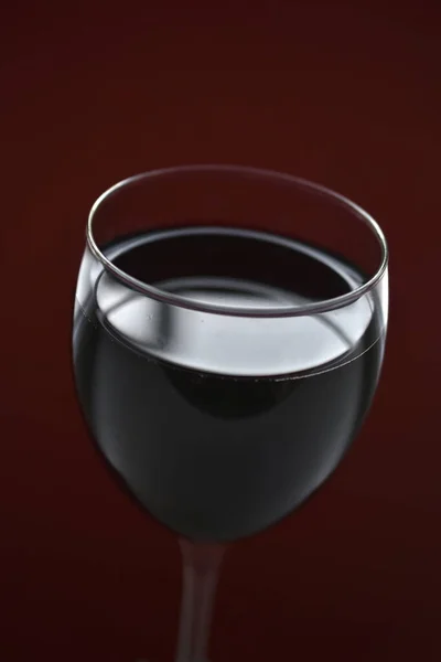 Large glass of red wine on a red background