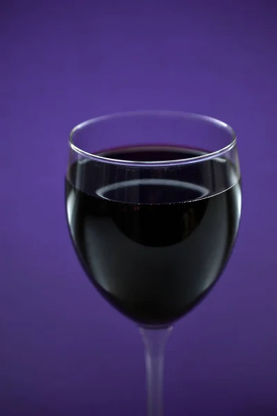 A large glass of red wine on a purple background
