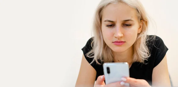 The girl reads bad news on the phone. Social networks. — Stock Photo, Image