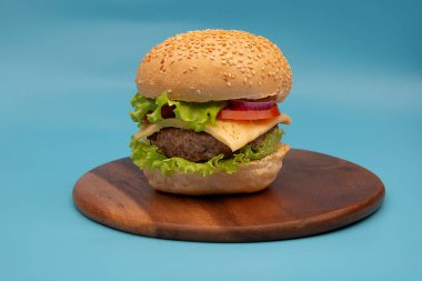 Mavi arka planda izole edilmiş taze lezzetli burger.