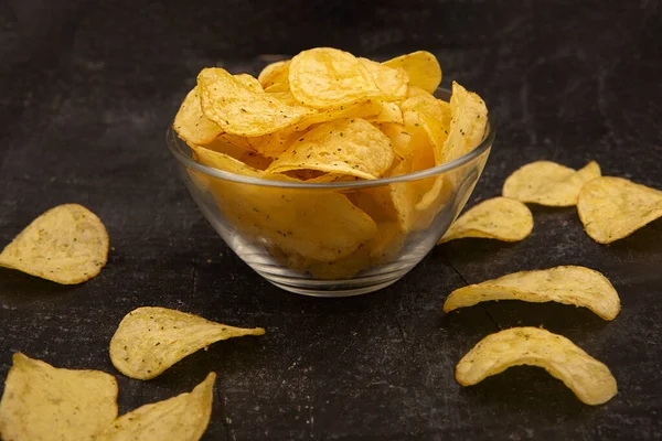 Potato chips on bowl isolated on a black background