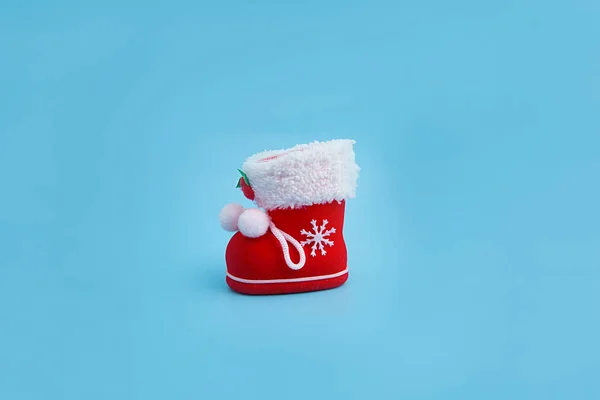 Mavi arka planda hediyeleri olan kırmızı Noel çizmesi.
