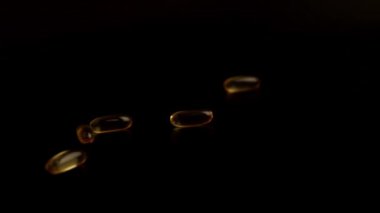 Bir sürü sarı yuvarlak hap. Omega ağır çekimde masaya düşüyor.