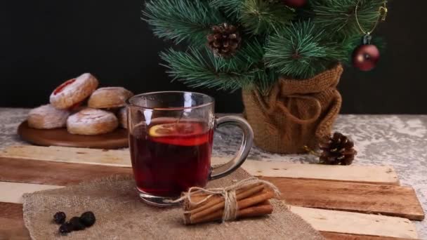 Karácsonyi forralt vörösbor fűszerekkel és gyümölcsökkel egy fa rusztikus asztalon. Hagyományos forró ital karácsonykor — Stock videók
