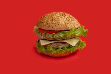 Kırmızı arkaplanda taze lezzetli bir burger izole edilmiş.