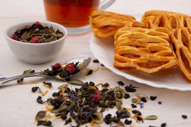 Ahşap bir masada reçelli bitki çayı ve kurabiyeler. Kahvaltı konsepti, ev yapımı kekler, tatlılık..