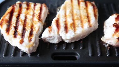 The chef turns the grilled meat over on the grill.