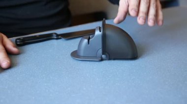 A man is sharpening a chef's knife on a knife stand.