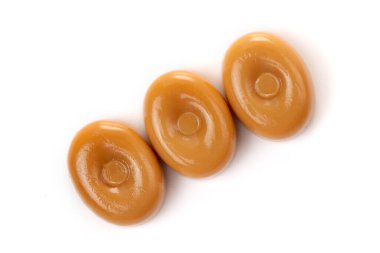 Beyaz arka planda üç karamel şekeri..