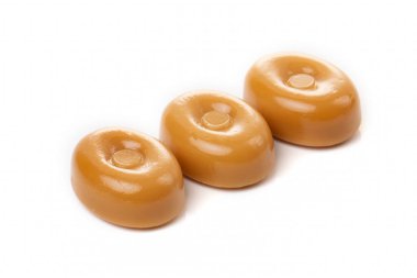 Beyaz arka planda üç karamel şekeri..