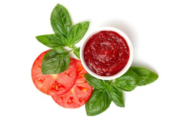 Fesleğen yaprakları ve beyaz arka planda domates dilimleri olan bir tencerede ketçap (domates ezmesi)..