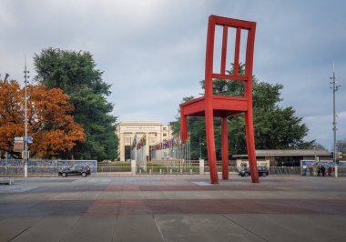 Cenevre, İsviçre - 03 Aralık 2019: Arkaplanda Cenevre, İsviçre - Arkaplanda Birleşmiş Milletler Sarayı (Birleşmiş Milletler Ofisi) ile sanatçı Daniel Berset 'in Kırık Sandalye Heykeli - Cenevre, İsviçre
