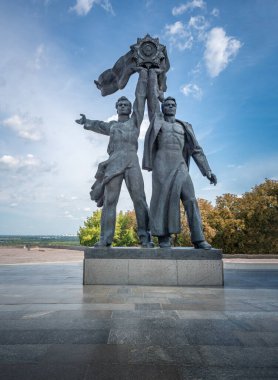 Rus ve Sovyet işçiler, Ukrayna 'nın Kiev kentindeki Halk Dostluğu Anıtı altında Sovyet Dostluk Nişanı' nı elinde tutuyorlar.