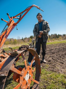 Yaşlı bir adam toprağı sürüyor.