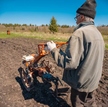 Yaşlı bir adam toprağı sürüyor.