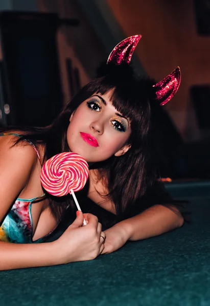 Девушка со сладостями в костюме дьявола — стоковое фото