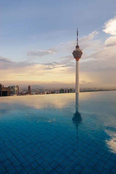 Hermoso reflejo de la Torre Kuala Lumpur junto a la piscina por la noche . — Foto de Stock