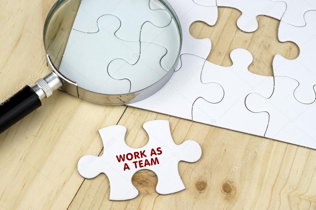 Magnifying glass on jigsaw puzzle against wooden surface