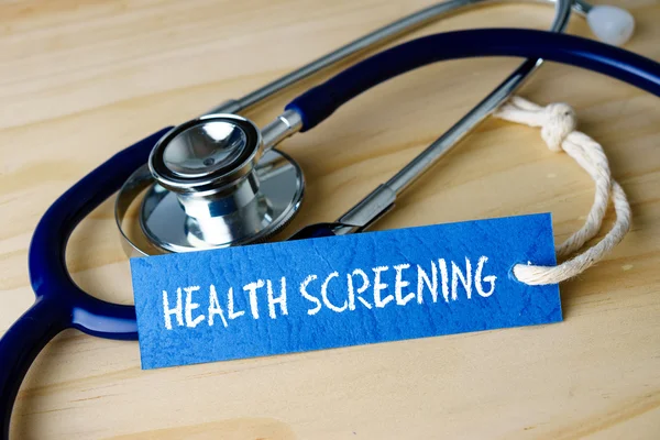 Image with HEALTH SCREENING words and stethoscope on wooden background. — Stock Photo, Image