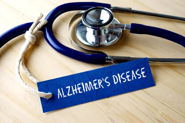 MALADIE D'ALZHEIMER mot inscrit sur l'étiquette et stéthoscope sur fond en bois . — Photo