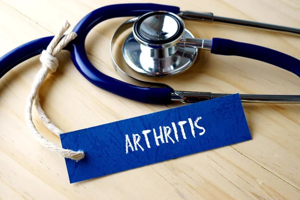 ARTHRITIS mot écrit sur étiquette et stéthoscope sur fond en bois . — Photo