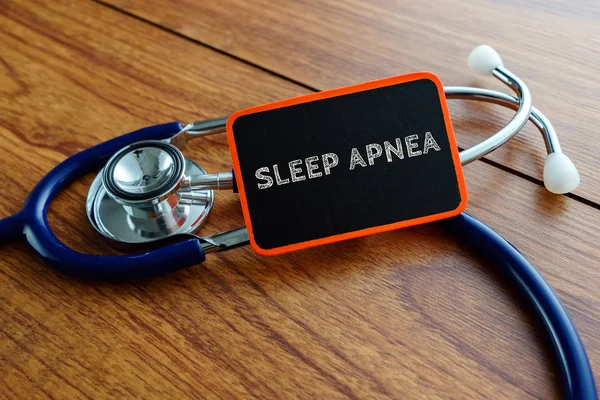 Слово SLEEP APNEA со стетоскопом на деревянном столе . — стоковое фото