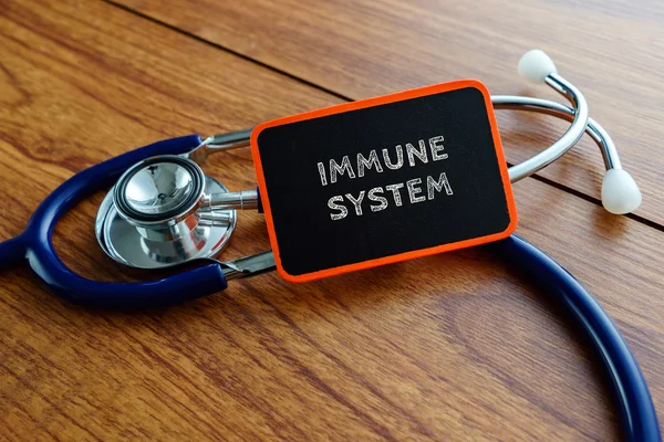 Word IMMUNE SYSTEM avec stéthoscope sur table en bois . — Photo