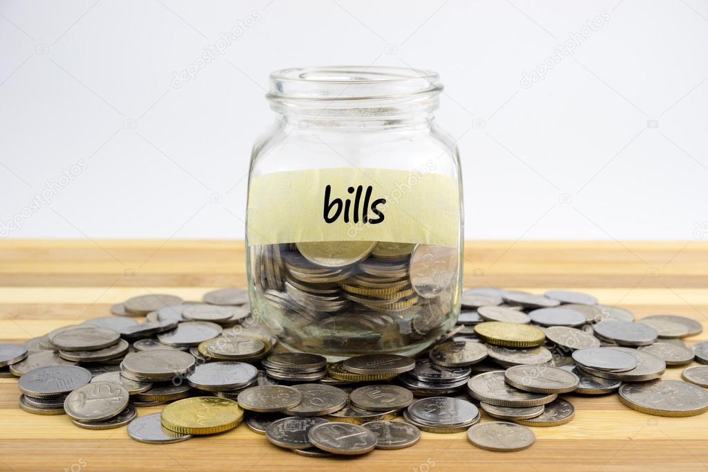 Coins in glass container on wooden surface