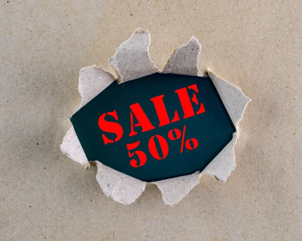 Roztrhaný hnědý hrubý papír s nápisem "prodej 50%" na pozadí. — Stock fotografie