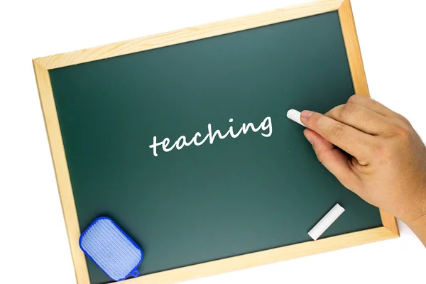Hand writing "teaching" word on green chalk board with white background. — Stock Photo, Image