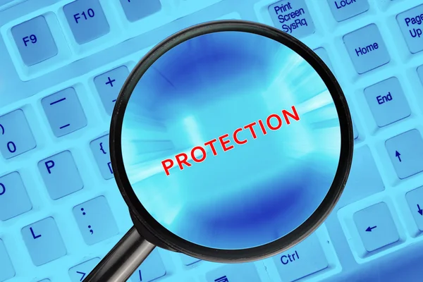 Lupa en el teclado de la computadora con la palabra "Protección" . — Foto de Stock